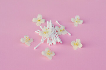 White buds near white jasmine flowers on light pink, close up. Skincare product for everyday beauty routine. Beauty concept. flat lay