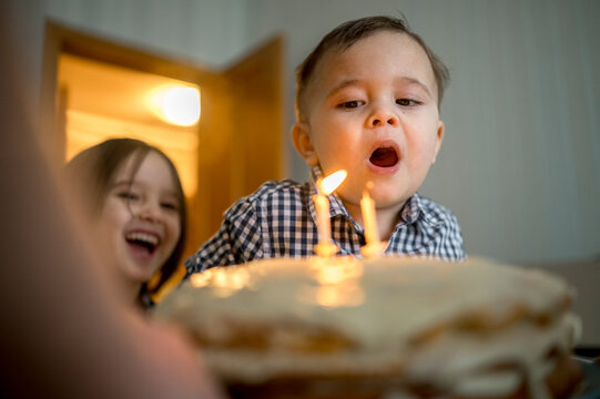 Boy blowing candles on cake and celebrating his birthday at home