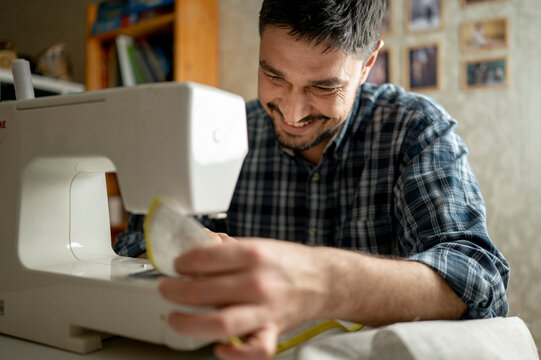 Smiling man using sewing machine at home