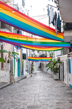 Spain, Balearic Islands, Ibiza, Rainbow flags hanging over town alley