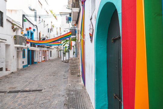 Spain, Balearic Islands, Ibiza, Rainbow flags hanging over town alley