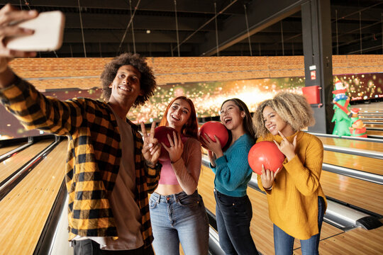 Young man taking selfie through smart phone at bowling alley