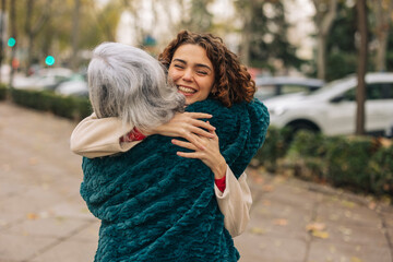 Happy granddaughter hugging grandmother at footpath