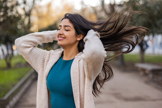 Happy Woman With Hands In Hair Enjoying At Park