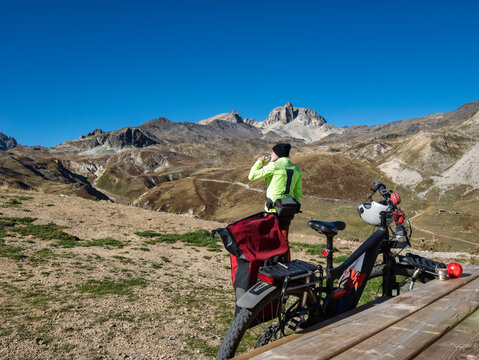 Senior man drinking water in front of mountain bike at Vanoise National Park, France