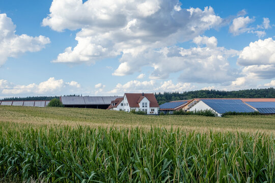 Germany, Bavaria,Augsburg,Clouds floating over countryside field with rural houses equipped with solar panels in background