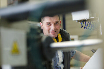 portrait of cheerful worke looking at camera at modern factory