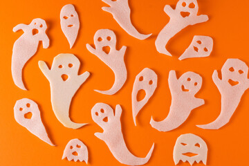 White ghosts kids craft for Halloween. Paper ghost on orange background top view. A scary and funny...