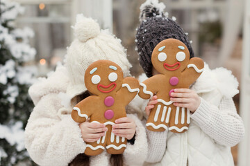 Sister and brother covering face with gingerbread man cookies
