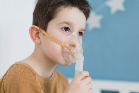 Sick boy wearing nebulizer mask at home