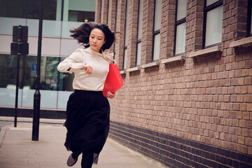 Businesswoman checking time and running on footpath