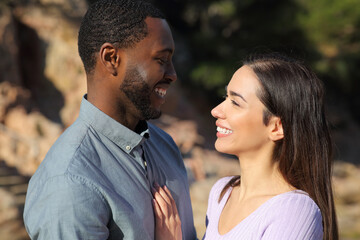 Interracial couple in love looking each other outdoors