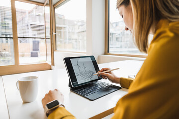 Young businesswoman with digitized pen drawing on tablet PC