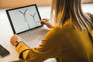 Businesswoman drawing wind turbine on laptop