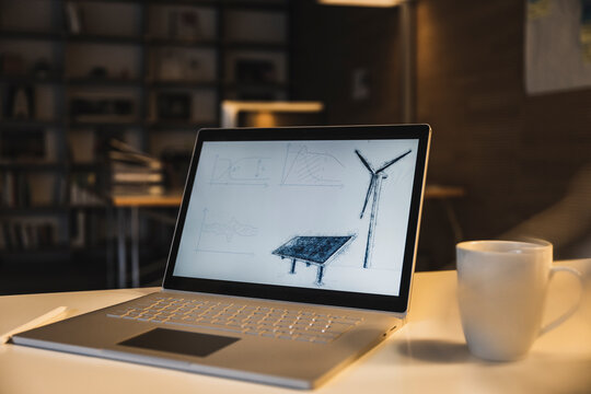 Laptop with solar panel and wind turbine drawing on screen