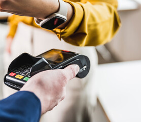 Young businesswoman paying with smart watch on card reader machine