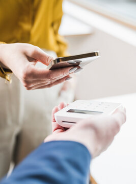 Hand of young businesswoman paying through smart phone on credit card reader