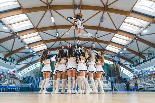 Full shot of a cheerleading squad hrowin one of their teammates high up in the air. Sport concept. High quality photo