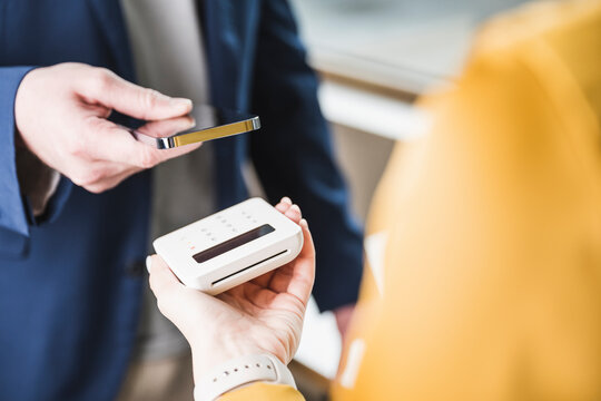 Young Businessman Paying Through Smart Phone On Card Reader Machine