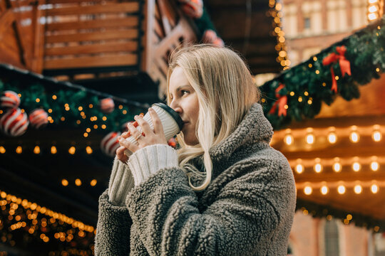 Blond woman drinking coffee at Christmas market
