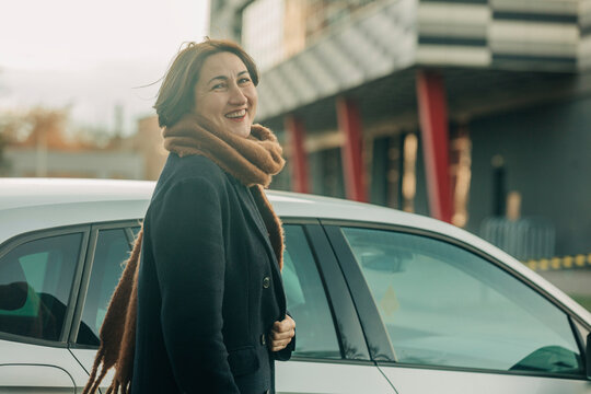 Smiling Mature Woman With Scarf Standing By Car