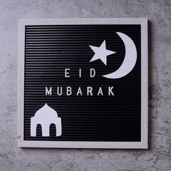 Eid mubarak word on letterboard arrange with islamic ornaments on gray background. 