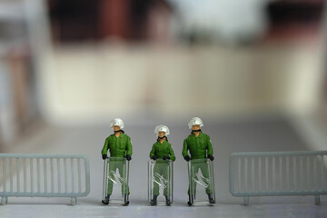 Miniature people toy figure photography. A military anti riot armored army standing on barricades, securing the road way - obrazy, fototapety, plakaty