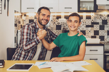Father is helping his son with learning. They are doing homework together.