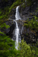 Fototapeta na wymiar Waterfall in Norway on a steep mountain with trees in the foreground