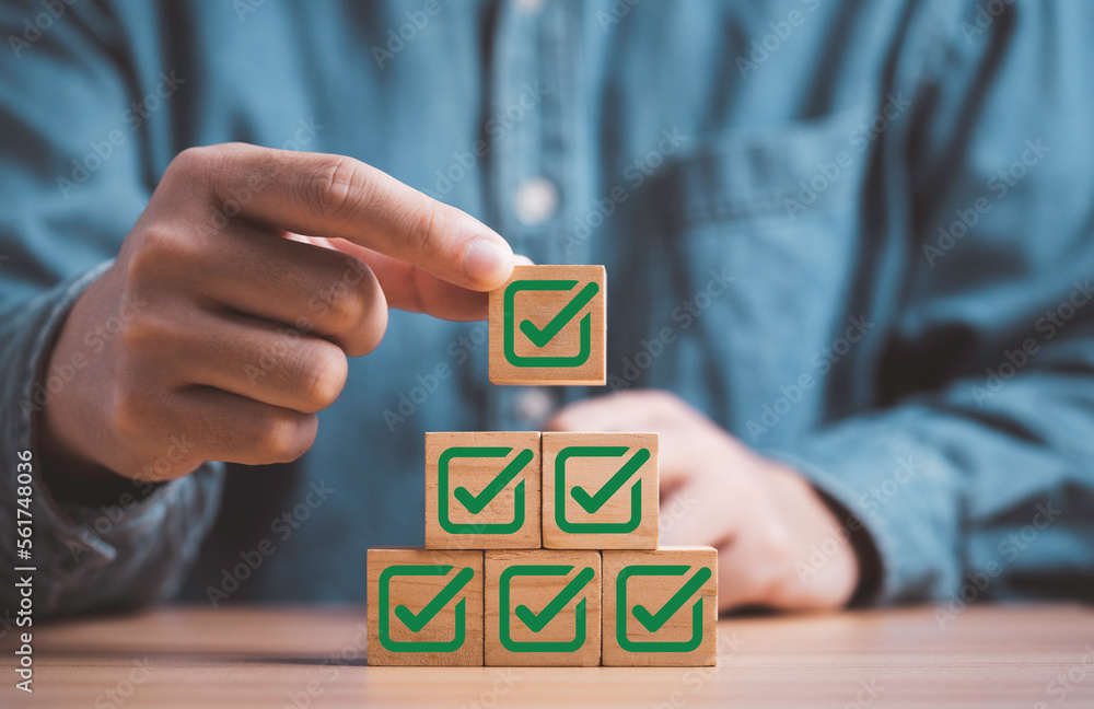 Poster Businessman stacking green correct sign symbol which print screen on wooden block cube for document and project approve concept.