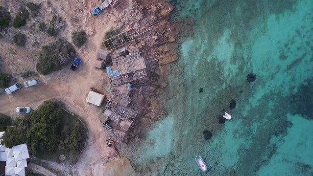 Boathouse red stony beach. Wonderful aerial view flight vertical bird's eye view drone formentera island ibiza spain, fall 2022. High Quality 4k Cinematic footage