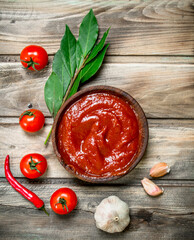 Tomato sauce in bowl with Bay leaf, garlic and tomatoes.