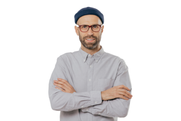 Horizontal shot of satisfied self confident male designer wears stylish headgear, dressed in white shirt, keeps arms folded, has dark stubble, isolated over white background. People and style concept