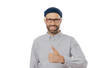 Positive smiling man with stubble, raises thumb up, demonstrates his like and approvement, wears headgear and formal shirt, isolated over white background. My answer yes. Gesturing. Body language