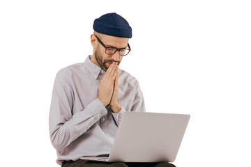 Professional male programmer keeps hans in praying gesture, looks at screen of laptop computer,...