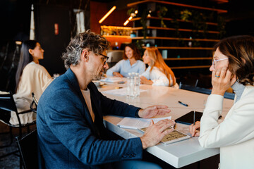 Mature colleagues discussing their project during offline meeting