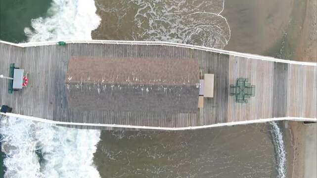 Atlantic Ocean, Belmar, New Jersey. Fishing pier made of wood, shooting from a drone. A place that needs to be seen, a route that is worth taking.