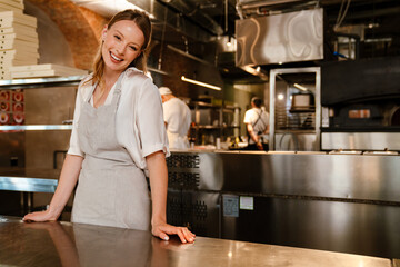 Young woman standing by counter while working in restaurant kitchen