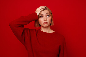 Young woman with short hair touching her head and looking upwards