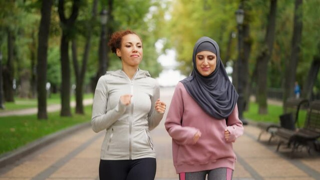Multiethnic female friends running in park together, active outdoor training