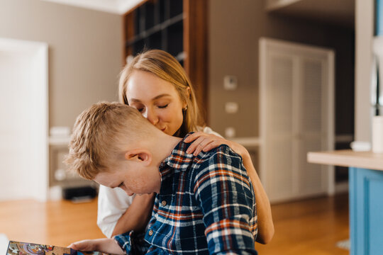 Loving mom kissing her son while standing in kitchen