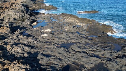 Spain, Lanzarote, Canary , Charco del Palo is a naturist village in the north of the island - drone aerial view of expanses of sand, black rocks black cliffs of volcanic lava origin and the ocean sea 