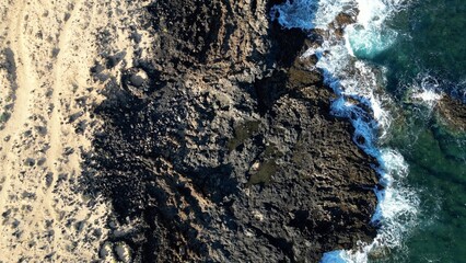 Spain, Lanzarote, Canary , Charco del Palo is a naturist village in the north of the island - drone aerial view of expanses of sand, black rocks black cliffs of volcanic lava origin and the ocean sea 