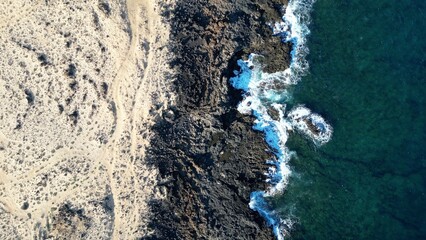 Spain, Lanzarote, Canary , Charco del Palo is a naturist village in the north of the island - drone aerial view of expanses of sand, black rocks black cliffs of volcanic lava origin and the ocean sea 