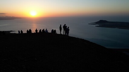 Spain, Lanzarote, Canary island - drone  view of people silhouette  on   amazing sunset in Mirador del Rio on the  Risco de Famara - Tourist looking the sun and the ocean sea - Travel in Lanzarote 
