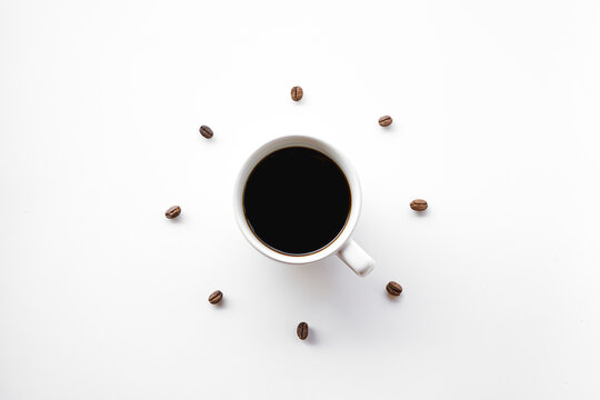 white coffee mug on white background with Coffee beans arrange as forming clock face.