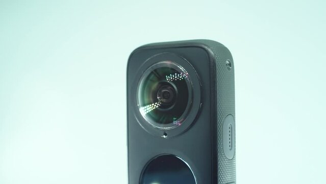 A close up shot of a 360 camera with dual lens, two lens covers, shiny studio lighting reflecting, round screen, on a rotating stand, slow motion, 4K video