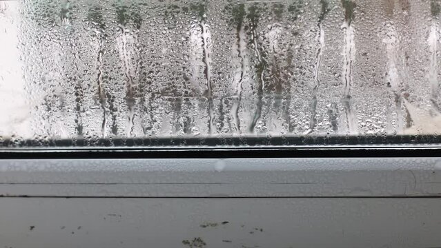 Glass with water drops of condensation. Water drops flow down the glass of window. 4K