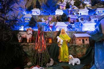 Christmas nativity crib scene in church. Shepherd with a lamb in his arms.