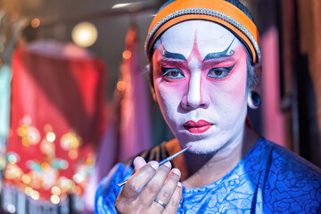 Chinese opera actor cosmetic make up painting face face before perform at back stage of theater